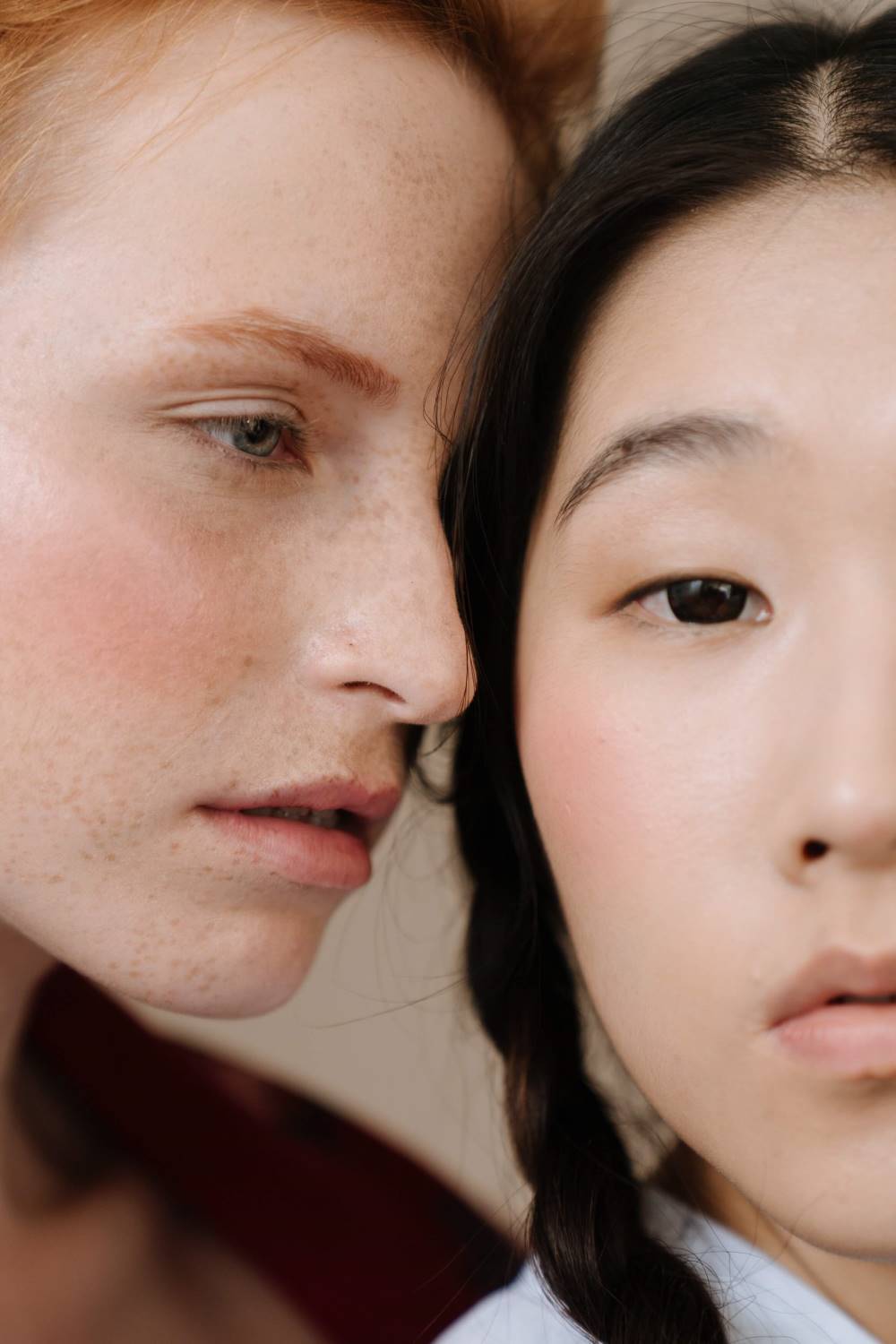 Two women with reddened cheeks, possibly due to broken capillaries, stand close to each other.